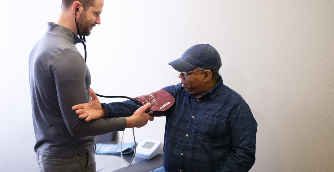 Gradient doctor taking a client's blood pressure as part of a DOT-compliant physical examination