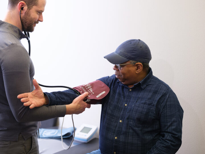 Gradient doctor taking a client's blood pressure as part of a DOT-compliant physical examination